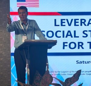 A speaker addresses attendees during a meeting focused on Social Stock Exchange and health-sector funding.