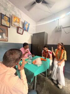 विद्यालय के कमरे में विदेशी मेहमान और स्कूल प्रतिनिधि बातचीत करते हुए