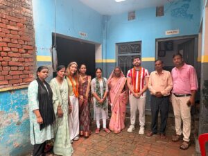 स्कूल परिसर में विदेशी मेहमान और विद्यालय परिवार के सदस्य समूह तस्वीर में