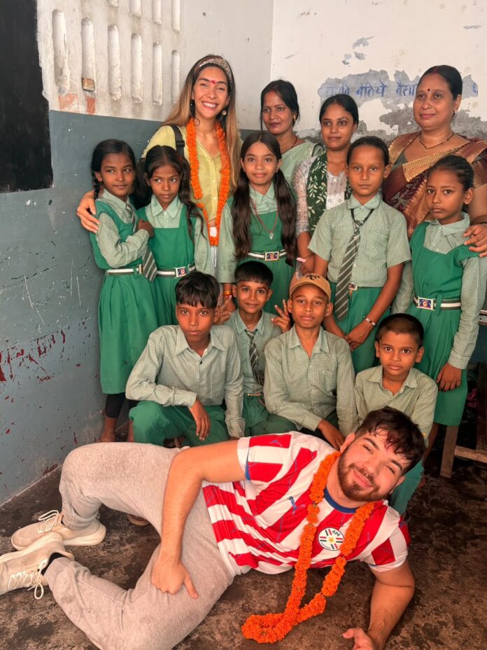विद्यालय की वर्दी पहने बच्चों के साथ विदेशी मेहमान की तस्वीर