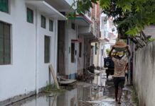 मऊ के वार्ड 12 में जलभराव से बेहाल लोग, 3 साल से नाली और सड़क का इंतजार जलभराव वाली गली में सामान लेकर जाता व्यक्ति